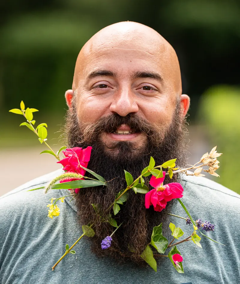 Francesco lacht, met rozen, lavendel en groene takjes in zijn lange baard